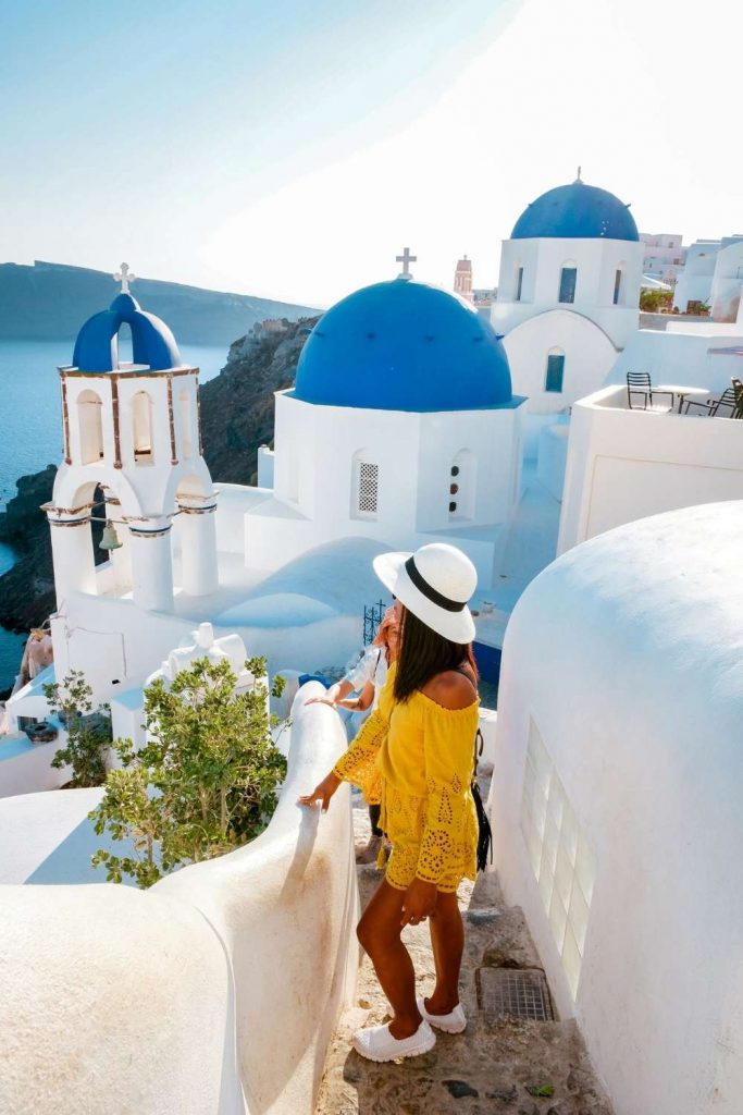 Santorini Sunshine Greece Outfit Ideas with a woman wearing a lacy yellow orange dress in Santorini