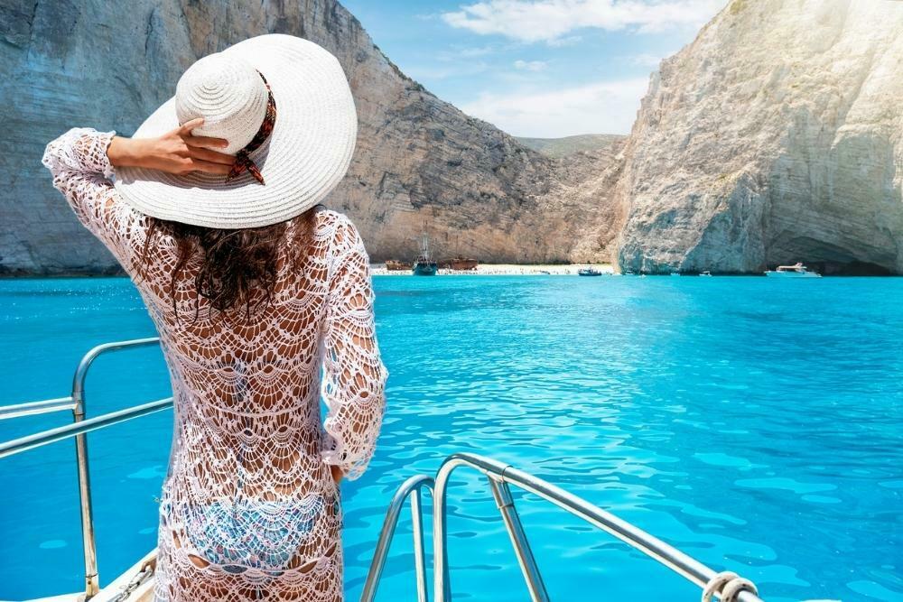 Girl on a boat wearing a white lace cover-up outfit for Greece near caves in Zakynthos
